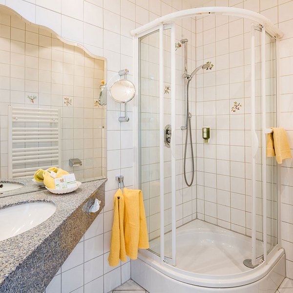 Blick ins Badezimmer mit Dusche rechts und Waschbecken links im Bild
